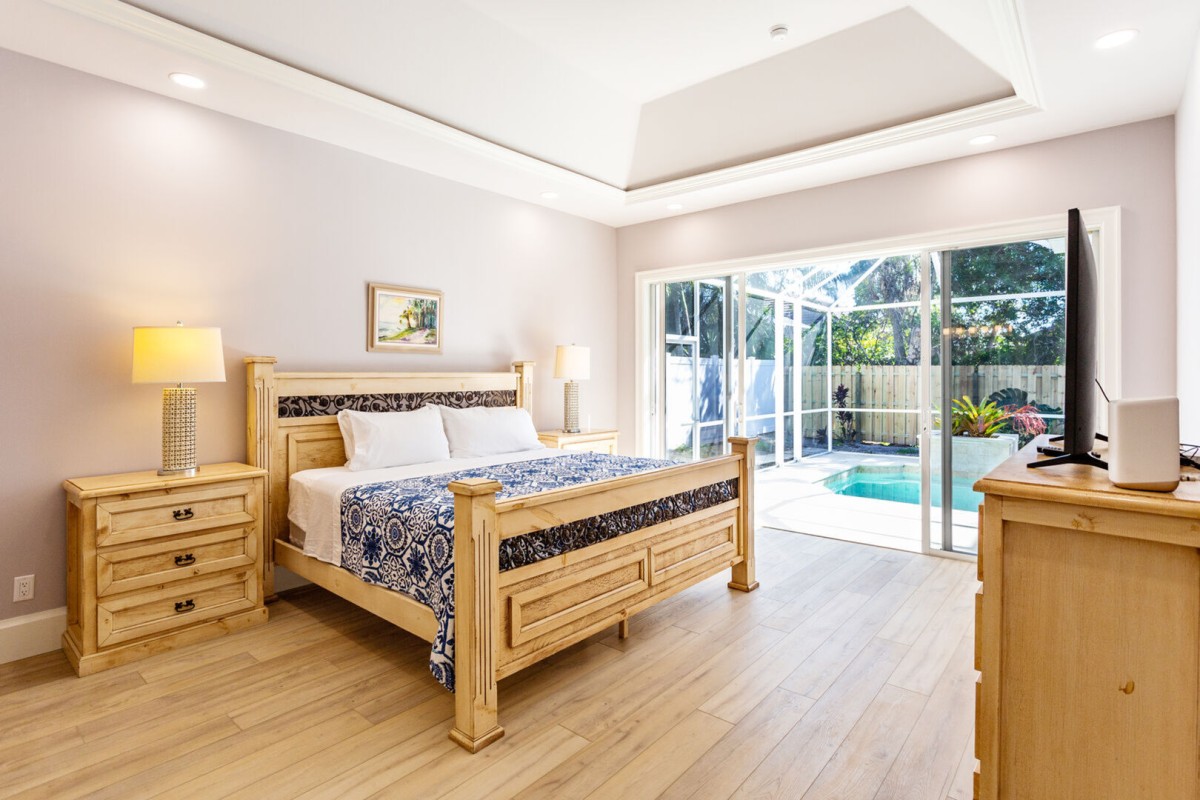 Master bedroom with king bed, tv and entrance to the pool